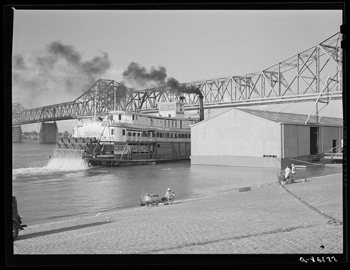 Riverboat carrying cargo leaving dock along waterfront. Louisville, Kentucky. Ohio River