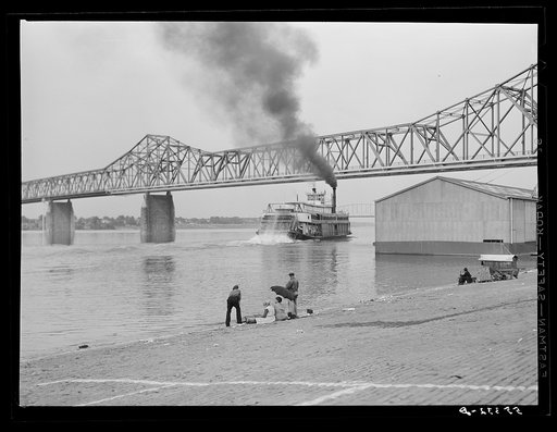 Riverboat carrying cargo leaving dock along waterfront on Ohio River. Louisville, Kentucky