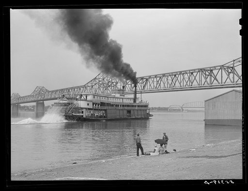 Riverboat carrying cargo leaving dock along waterfront on Ohio River. Louisville, Kentucky