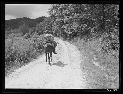 Rural mailman taking packages and saddlebags of letters, which have been transferred from a wagon which cannot go up the bad side roads and creek beds, to the mountain families in this isolated area. Near Morehead, Kentucky