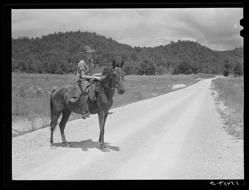 Rural mailman who has brought the mail to the crossroads transfers letters and packages to another postman's saddlebags. This rider takes the mail further up the side road and creek beds where no wagon or car can go. In the mountains section near Morehead, Kentucky