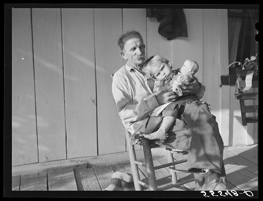 Mountaineer with neighbor's child on front porch of home up Frozen Creek. Breathitt County, Kentucky