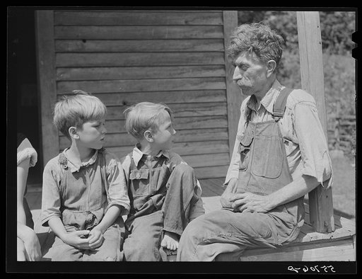 Mountaineer with his two grandsons whom he raised in his home with the help of the neighbors. He had been crippled with arthritis most of his life. On the steps of a schoolhouse on South Fork of Kentucky River. Breathitt County, Kentucky