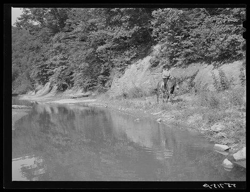 Mountaineer riding on muleback up a creek bed to his farm. Breathitt County, Kentucky