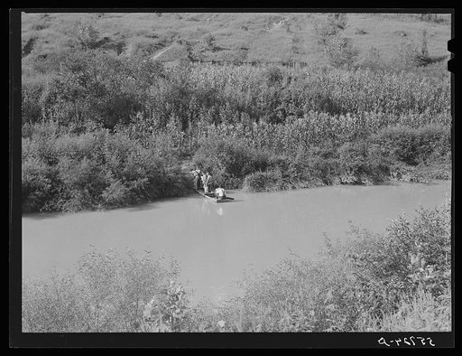 Crossing the creek in a boat from the main road to their home after returning from the store with groceries and supplies. Breathitt County, Kentucky