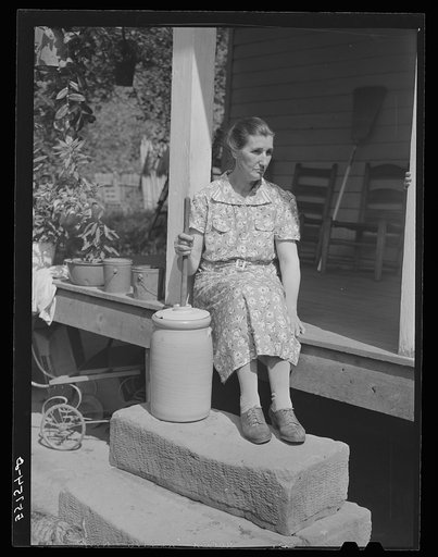 Mountain woman churning butter on the steps of front porch of her home. Up Burton's Fork off Middle Fork of the Kentucky River. Breathitt County, Kentucky