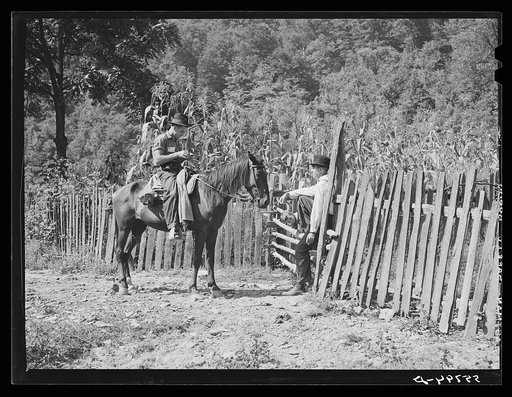 The mailman serves as a newspaper too in the isolated regions of the Kentucky mountains. Here he is discussing events with a mountaineer who lives up a creek bed. South Fork of the Kentucky River, near Jackson, Kentucky
