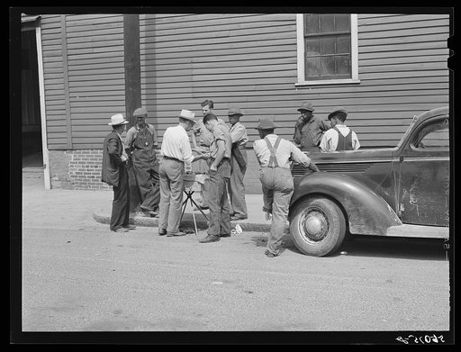 Peddler selling patent medicines to farmers outside warehouse on opening day of tobacco market in Mebane, North Carolina, where many Caswell County farmers sell their tobacco at auction