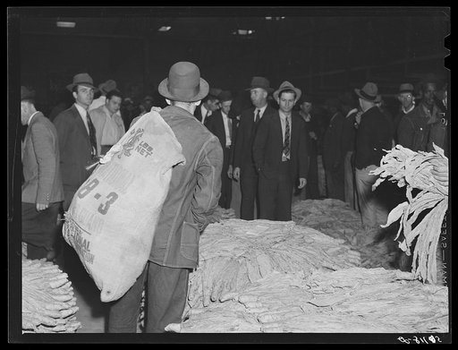 Farmers waiting around during tobacco auction sale in warehouse. Danville Virginia