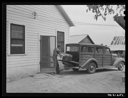 Untitled photo, possibly related to: E.O. Foster's son taking the empty milk bottles out of their delivery wagon to be washed and refilled in the pasteurizing plant of their Caswell dairy. They are FSA (Farm Security Administration) tenant purchase borrowers. Caswell County, North Carolina