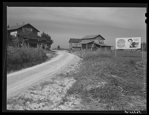 Untitled photo, possibly related to: Tobacco barns and cigarette advertisements on country road in Prospect Hill section. Caswell County, North Carolina