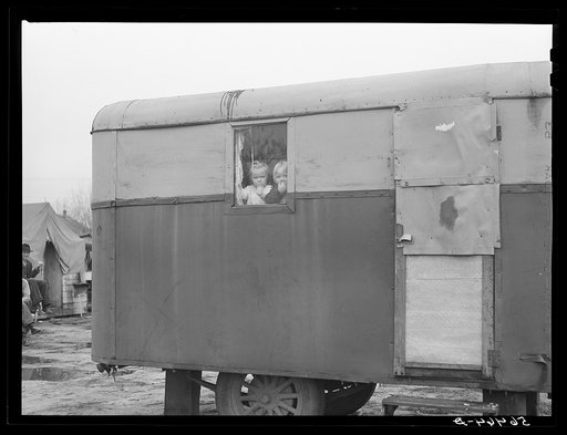 Untitled photo, possibly related to: Children looking out of trailer window. Trailer where C.E. Children and family live in highway about three miles from Fort Benning. He is an auto mechanic and came up to Columbus, Georgia two weeks ago from Albany, Georgia and now works at Columbus Motor Company.