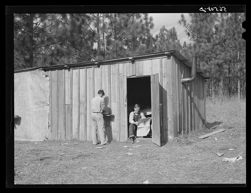 Construction workers from Monroe, Louisiana, washing in front of their shack. Water must be hauled from a nearby church faucet. They are living on government property (no rent) while working at Camp Livingston near Fort Beauregard, Alexandria, Louisiana