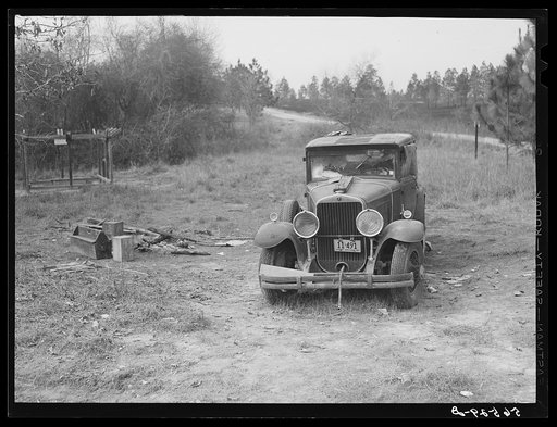 Untitled photo, possibly related to: Close-up of car from Mississippi used for sleeping as well as shelter and traveling. Evidences of cooking outdoors are beside it. On highway near Camp Livingston, Alexandria, Louisiana