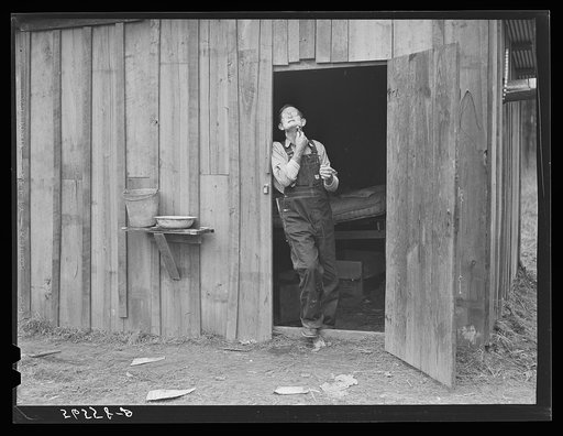 Charles B. Griggs shaving in front of his self-built shack on government property near Camp Livingston. He used to work on his farm outside Monroe, Louisiana, but came to work on construction job at Camp Livingston near Fort Beauregard because he could make more money