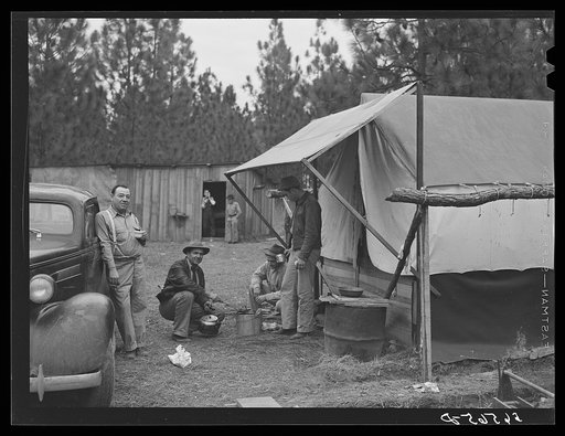 Untitled photo, possibly related to: Camp Livingston construction worker cooking outdoors in front of shacks which they have built themselves out of lumber they purchased or found nearby. These are along the main highway on government property so they do not have to pay rent. Water is hauled from a 