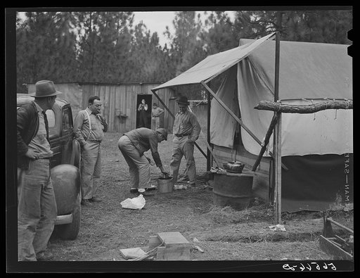 Camp Livingston construction worker cooking outdoors in front of shacks which they have built themselves out of lumber they purchased or found nearby. These are along the main highway on government property so they do not have to pay rent. Water is hauled from a nearby church faucet. There are no sa