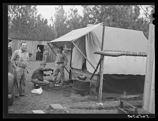 Untitled photo, possibly related to: Camp Livingston construction worker cooking outdoors in front of shacks which they have built themselves out of lumber they purchased or found nearby. These are along the main highway on government property so they do not have to pay rent. Water is hauled from a 