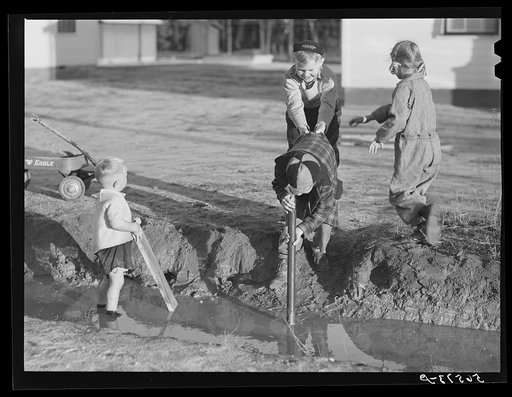 Children of Army men's families on Milstead Avenue playing in water in front of their new homes five miles outside of Columbus, Georgia
