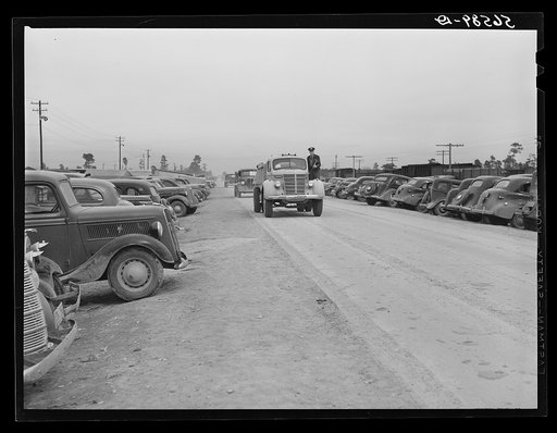 Cars of construction workers parked along highway by entrance to Camp Claiborne. Alexandria, Louisiana