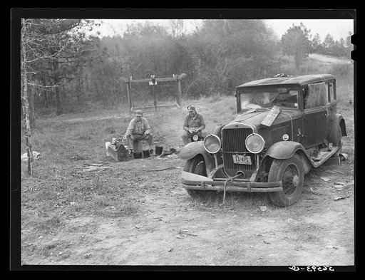 Untitled photo, possibly related to: Close-up of car from Mississippi used for sleeping as well as shelter and traveling. Evidences of cooking outdoors are beside it. On highway near Camp Livingston, Alexandria, Louisiana