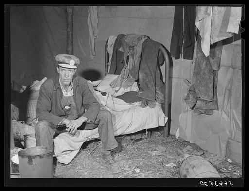 Untitled photo, possibly related to: Interior of shack described in other pictures. Mr. W.R. Carpenter of Beaumont, Texas also a truck driver, seated on bed. Men very willing to have photo made, saying they should cooperate in this undertaking as they were all free Americans and hoped for better con