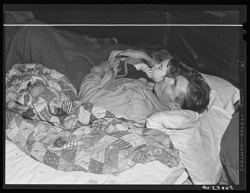 Carpenter and construction worker from Georgia who is recovering from flu.  Next to him is a neighbor's child and his wife is going to take in two other neighbor's children with them because their tent leaks so badly after a week of heavy rains and winds. In this same tent live about ten men, two wo