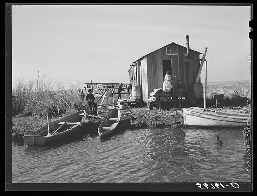 Spanish trappers' camp in the marshes. In the small "peroque" [i.e. pirogue] (or canoe) he can go up the very narrow and shallow bayous; the large boat he uses for fishing, going to the island to sell his muskrat pelts, and bringing back supplies. Delacroix Island, Saint Bernard Parish, Louisiana