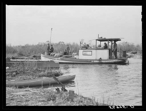 Spanish trapper and his family returning home from the island with groceries and supplies for their marsh camp. On the bow of the boat they still have their sacks of muskrat pelts which they refused to sell at the auction because the fur buyers' prices were too low. Delacroix Island, Saint Bernard P
