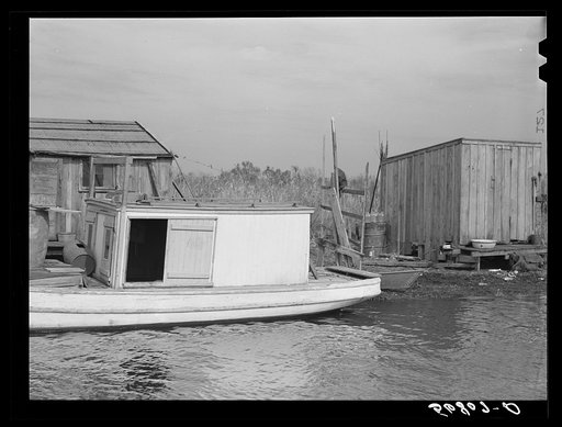 Untitled photo, possibly related to: Spanish trapper's camp in the marshes. In the small "piroque"(or canoe) he can go up the very narrow and shallow bayous; the large boat he uses for fishing, going to the island to sell his muskrat pelts, and bringing back supplies. Delacroix Island, Saint Bernard