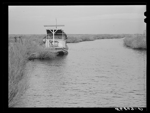 A Spanish muskrat trapper's boat in a bayou by his marsh camp. He uses this large boat in other seasons for fishing and shrimping. Delacroix Island, Saint Bernard Parish, Louisiana