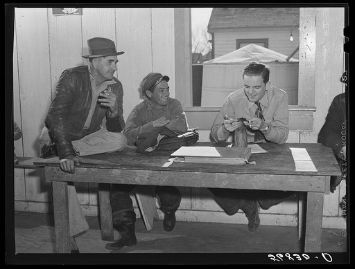 FSA (Farm Security Administration) Supervisor examining one of the trapper's furs during an auction sale held in a dance hall on Delacroix Island, Saint Bernard Parish, Lousiana