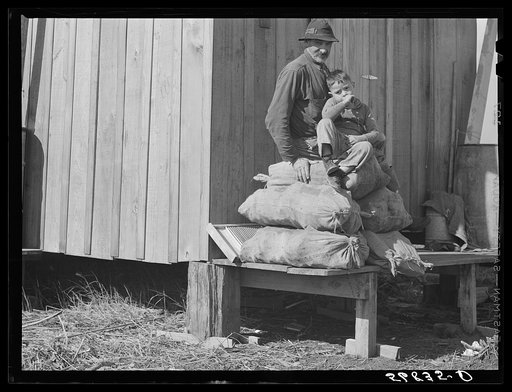 Spanish muskrat trapper and his grandson sitting on sacks of dried muskrat pelts, in front of their camp in the marshes. Delacroix Island, Saint Bernard Parish, Louisiana