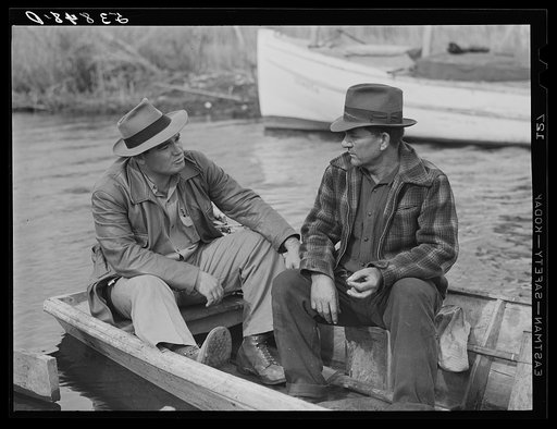FSA (Farm Security Administration) supervisor talking to one of the trappers in his boat by one of the bayou marsh camps. Delacroix Island, Saint Bernard Parish, Louisiana