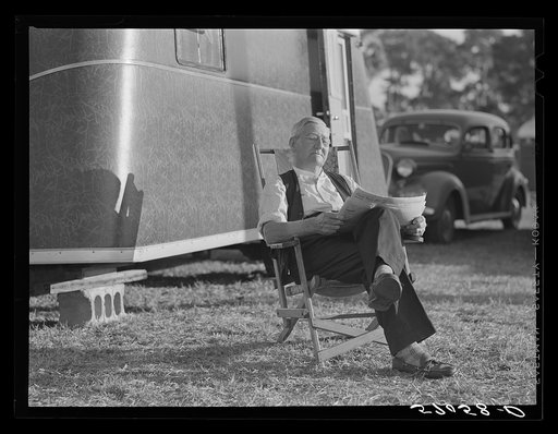 Reading the newspaper outside his trailer home. Sarasota trailer park, Sarasota, Florida