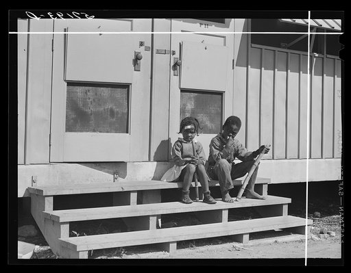 Children of agricultural laborers sitting on steps of metal shelters in Okeechobee migratory labor camp. Belle Glade, Florida