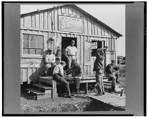 Migratory laborers playing checkers in front of jook joint during slack season for vegetable pickers. Belle Glade, Florida
