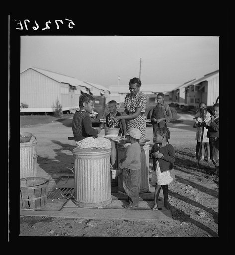 Washing greens by pump near metal shelters at Okeechobee migratory labor camp. Belle Glade, Florida