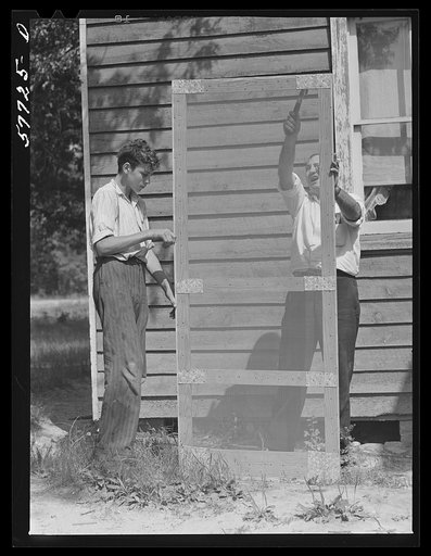 Door frame with screen wire assembled ready to fasten on hinge strip. Screening demonstration. Charles County, La Plata, Maryland