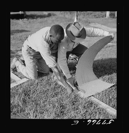 Cutting metal reinforcement strips to fit the screen door joints. Screening demonstration. Saint Mary's County, Ridge, Maryland