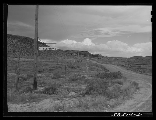 Sign at crossroads pointing direction to nearest telephone in ranch country. Birney, Montana