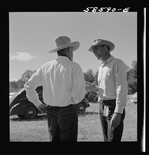 Lyman Brewster from Quarter Circle U Ranch in Birney, Montana, talking to a neighbor stockman at stockmen's picnic and barbecue. Spear's Siding, Wyola, Montana