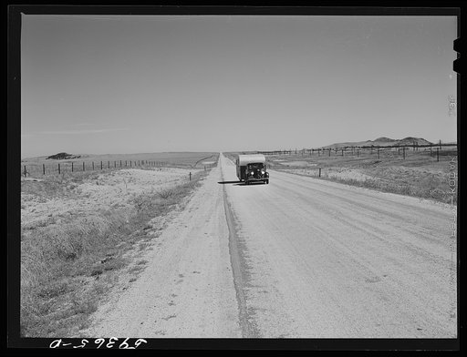 Passenger car and trailer enroute to California on highway across plains between Cheyenne and Laramie, Wyoming