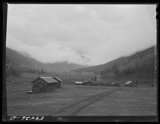 Untitled photo, possibly related to: Cabins on ranch. Mist and clouds over mountains before an early blizzard