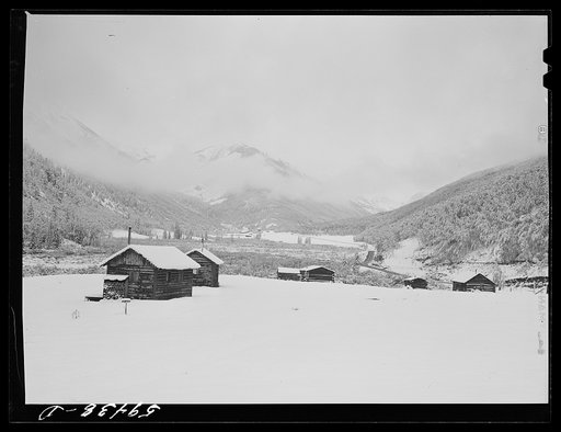 Untitled photo, possibly related to: Cabins on ranch. Mist and clouds over mountains before an early blizzard
