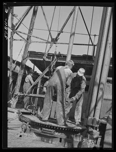Oil workers pulling up old pipe to change bit on drilling pipe at bottom of oil well in C.C. Graber pool of Continental oil company. Moundridge area near McPherson, Kansas