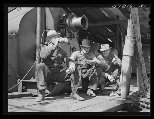 C.L. Saxton, driller; J.G. Betz, Cathead man; and L.C. Westerman, eating lunch around oil well in C.C. Graber pool of Continental oil company. Moundridge area near McPherson, Kansas