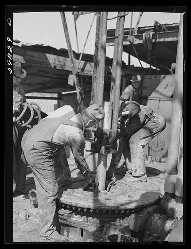 Oil workers pulling up old pipe to change bit on drilling pipe at bottom of oil well in C.C. Graber pool of Continental oil company. Moundridge area near McPherson, Kansas