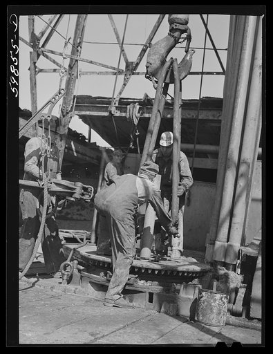 Untitled photo, possibly related to: Oil workers pulling up old pipe to change bit on drilling pipe at bottom of oil well in C.C. Graber pool of Continental oil company. Moundridge area near McPherson, Kansas