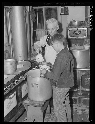 Young boy receiving pail of soup in kitchen of city mission. Dubuque, Iowa